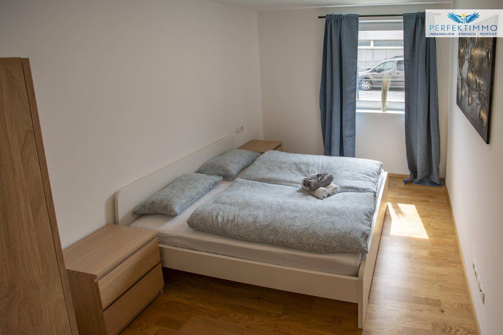 Schlafzimmer mit Doppelbett, Nachttisch und Blick aus dem Fenster.
