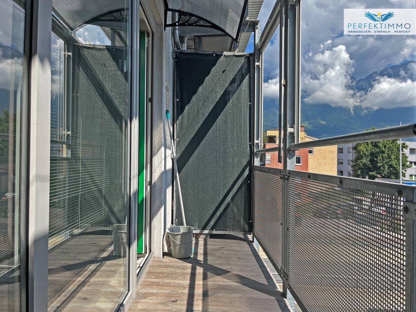 Schmaler Balkon mit Metallgeländer und Bergblick unter bewölktem Himmel.
