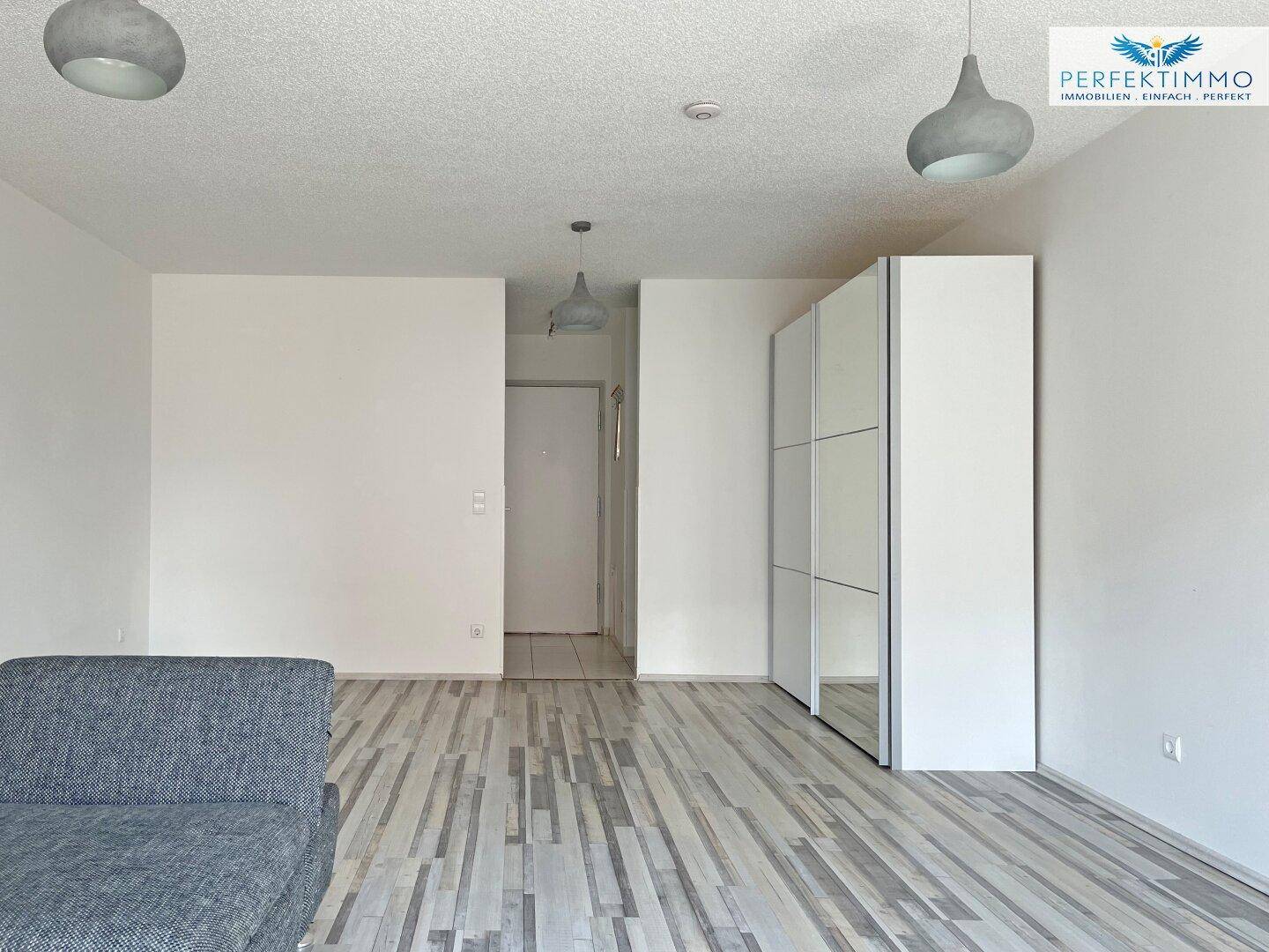 Heller Eingangsbereich mit Laminatboden und weißem Einbauschrank.