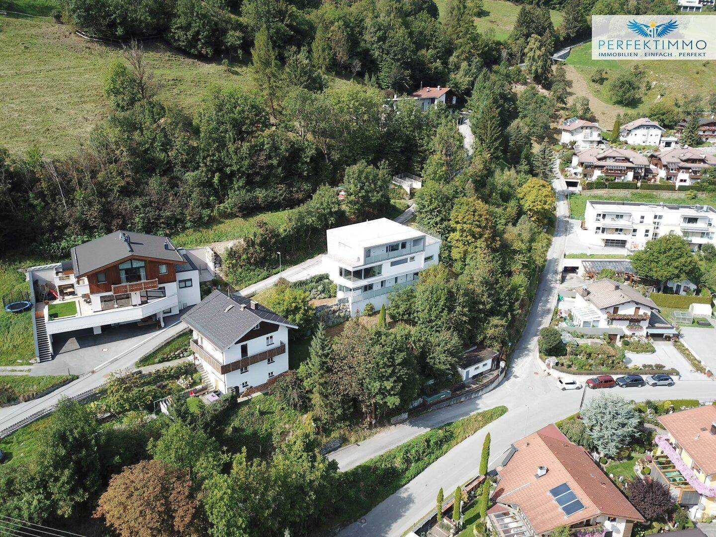 Luftaufnahme einer Wohnsiedlung mit dem modernen Gebäude, eingebettet in eine grüne Hügellandschaft.