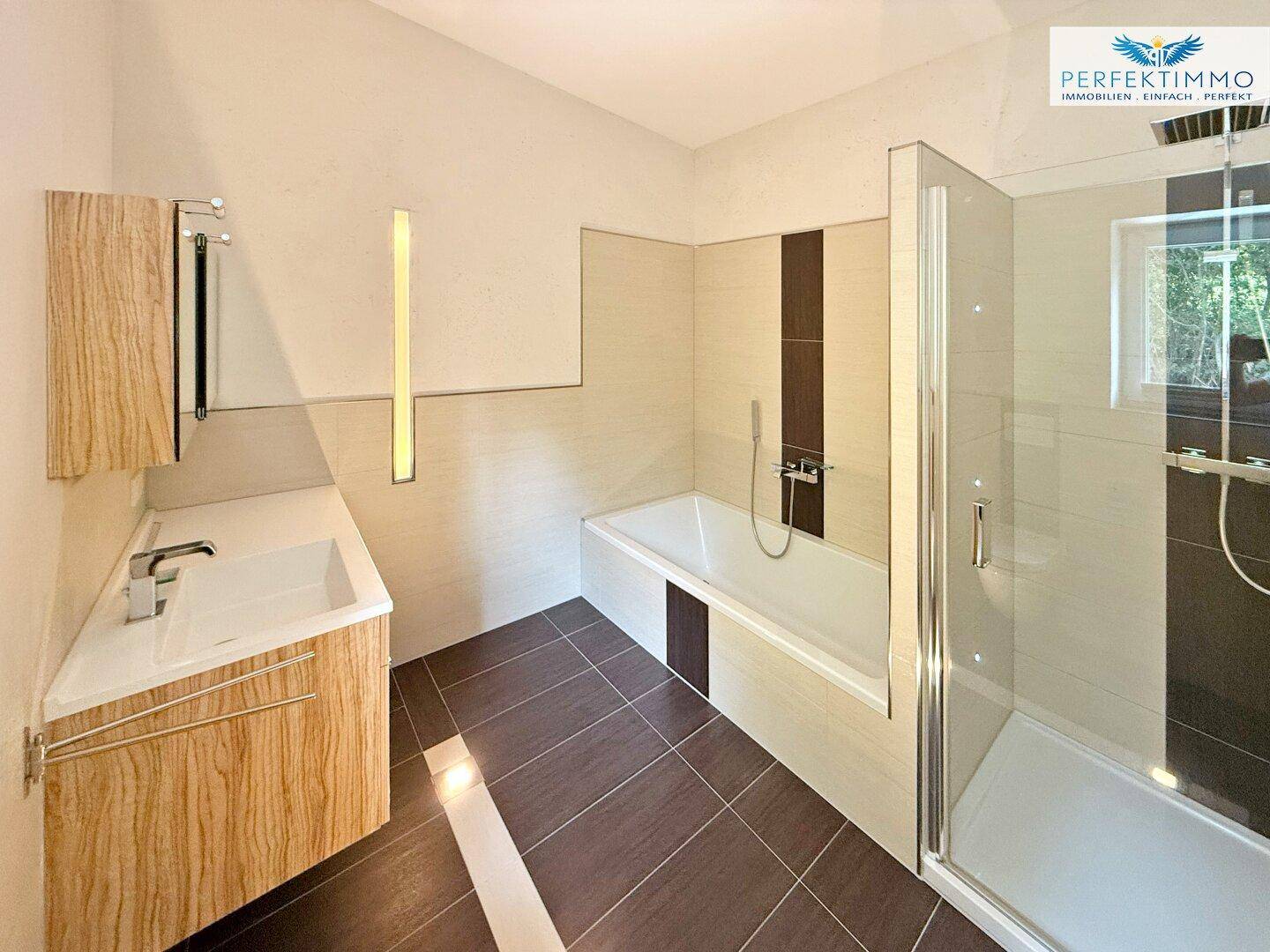 Modernes Badezimmer mit Badewanne, Duschkabine, Waschtisch und Fenster für natürliches Licht.