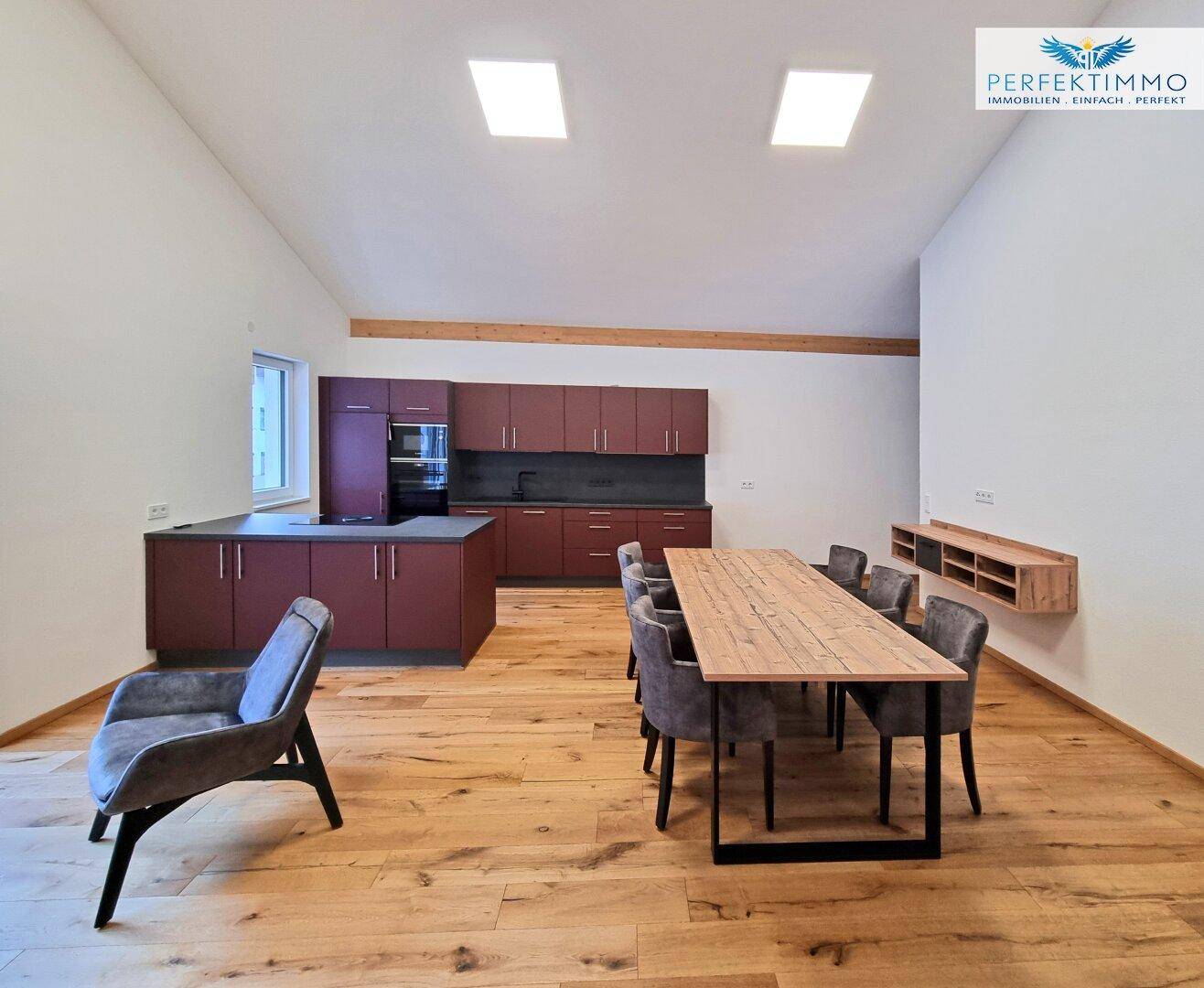 Moderne Einbauküche in dunklem Rot mit Holzboden und hohen Decken.
