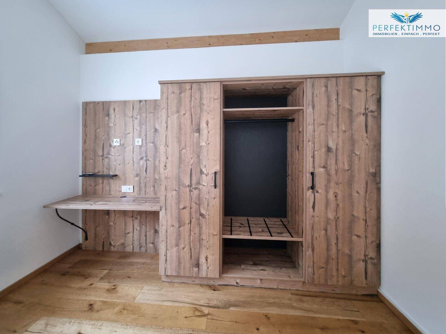 Maßgefertigter Holzschrank mit integriertem Schreibtisch und Ablageflächen.