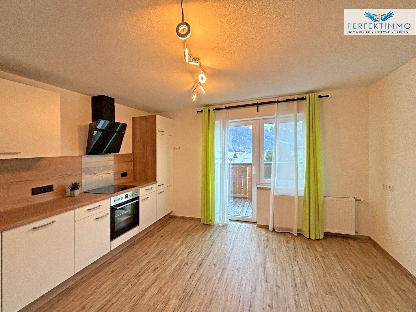 Offene Küchenzeile mit modernen Geräten und Zugang zu einem Balkon.