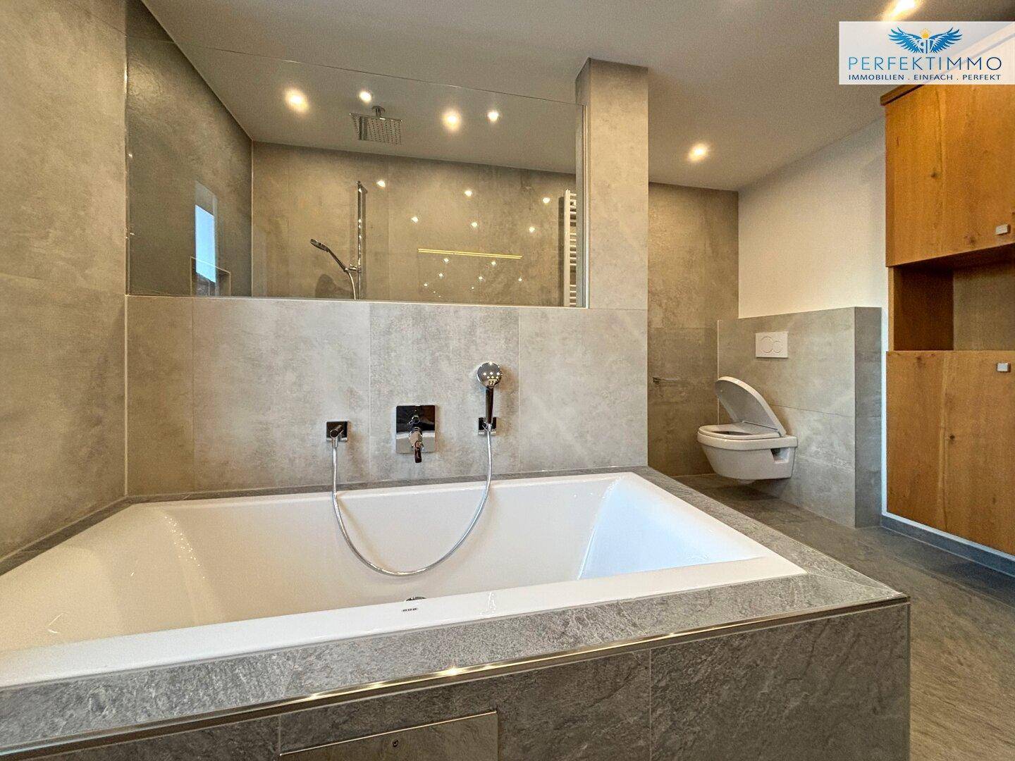 Geräumiges Badezimmer mit eingebauter Badewanne, Duschbereich und Wand-WC.