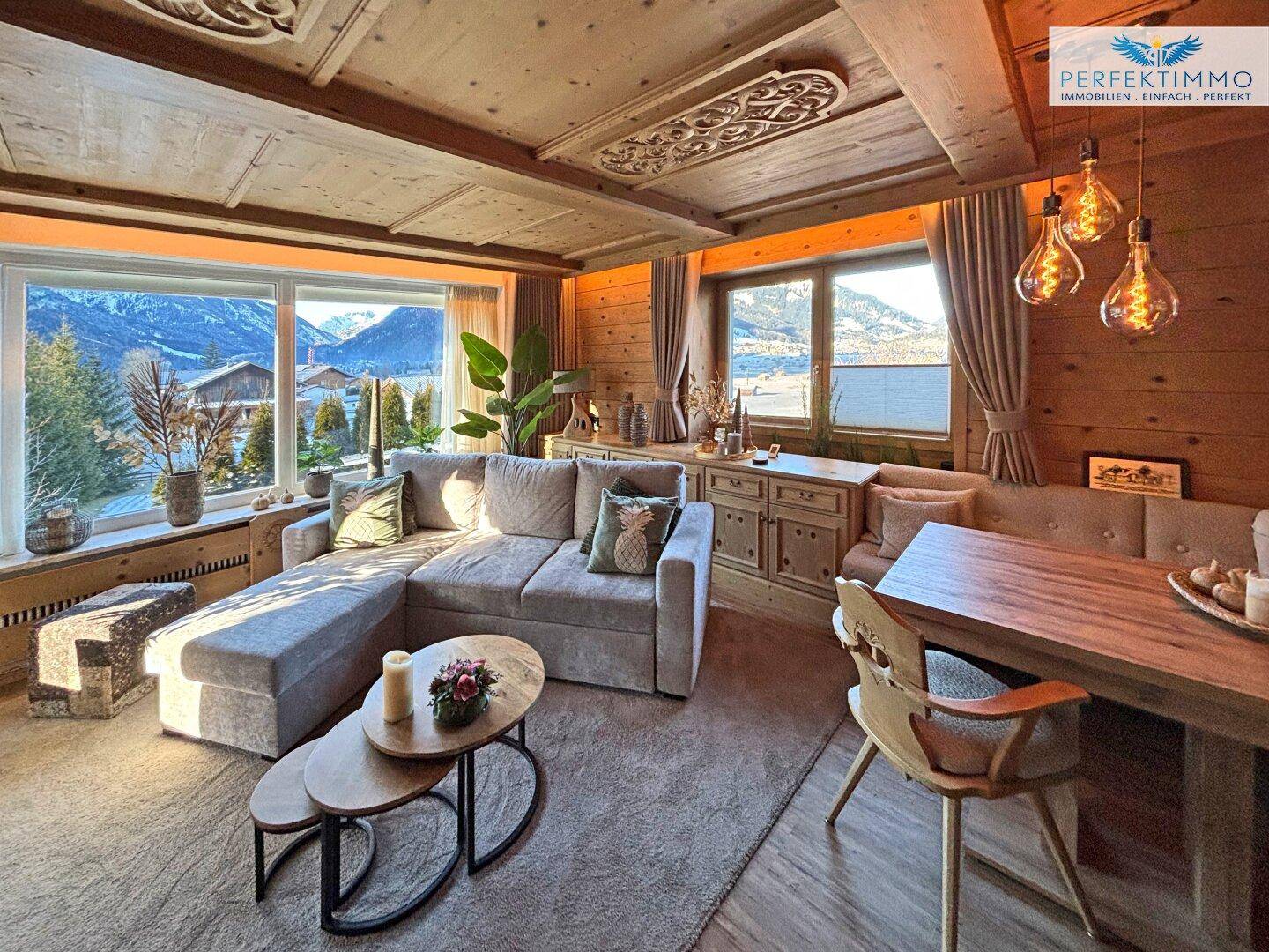 Gemütlicher Wohn-Essbereich im alpinen Stil mit Holzwänden, Decken und Bergblick.
