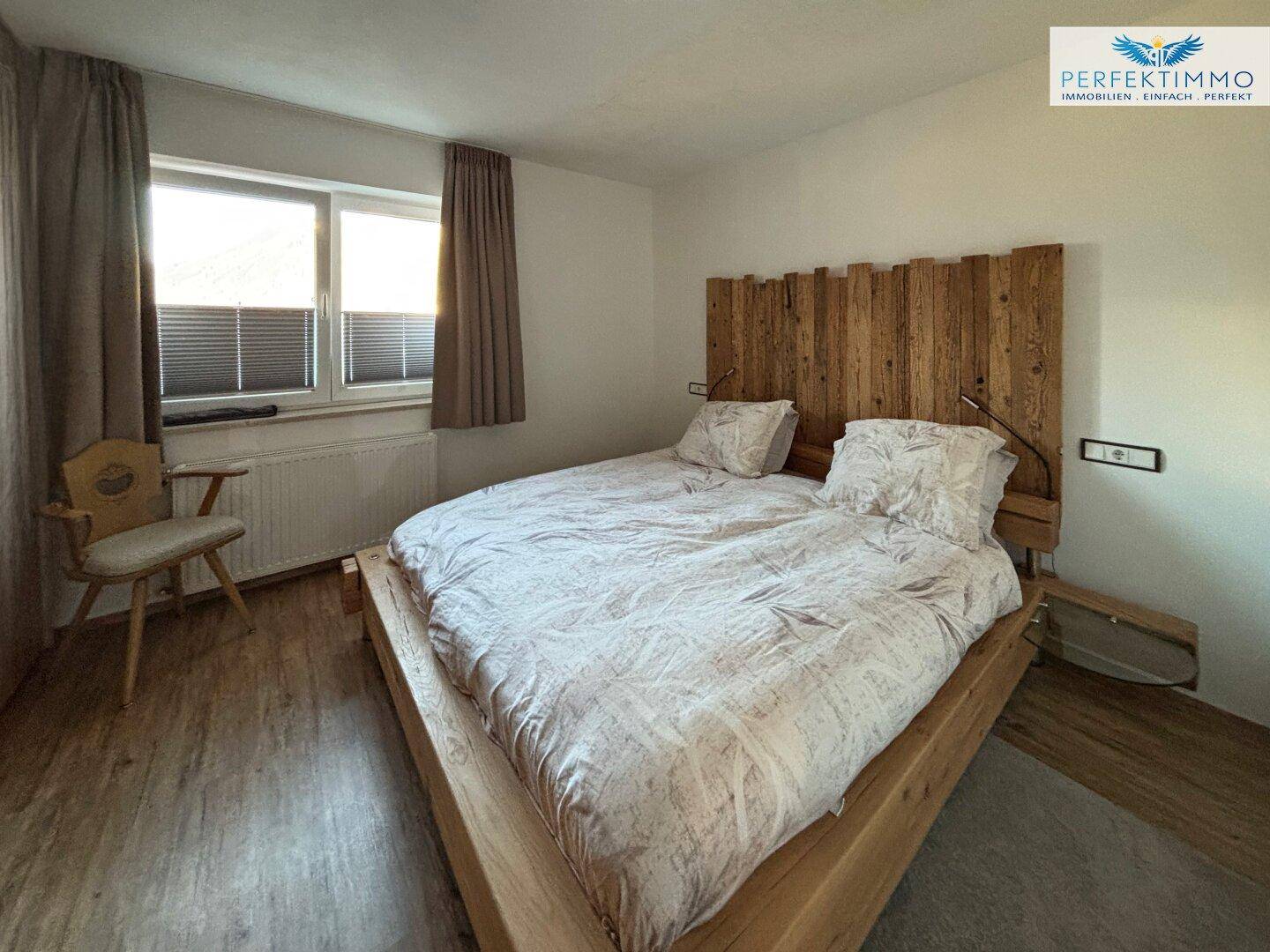 Gemütliches Schlafzimmer mit Holzbett und Blick auf die umliegende Landschaft.