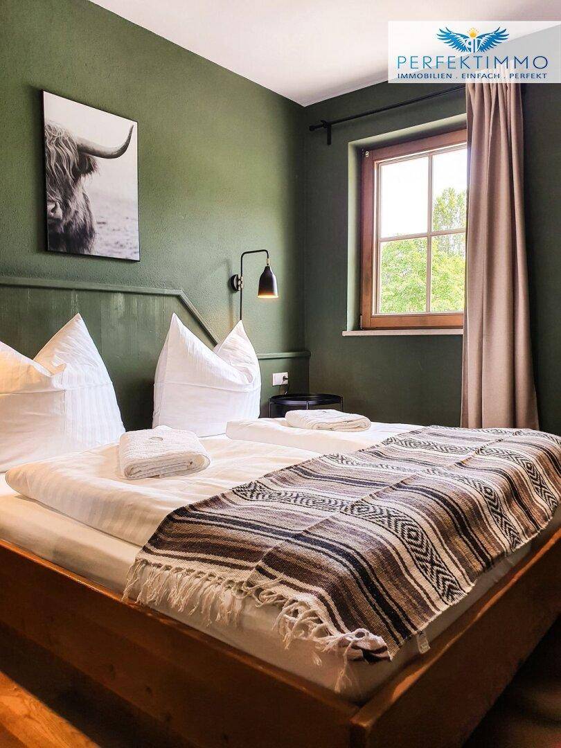Schlafzimmer mit grünen Wänden, Holzbett und rustikaler Decke.