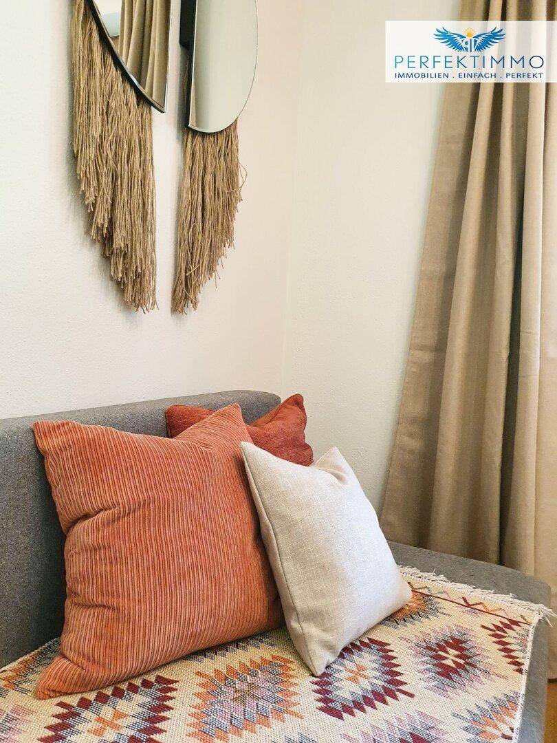 Gemütliches Sofa mit bunten Kissen und dekorativer Wandgestaltung.