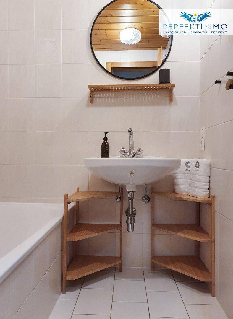 Helles Badezimmer mit Waschbecken, Badewanne und Holzdetails.