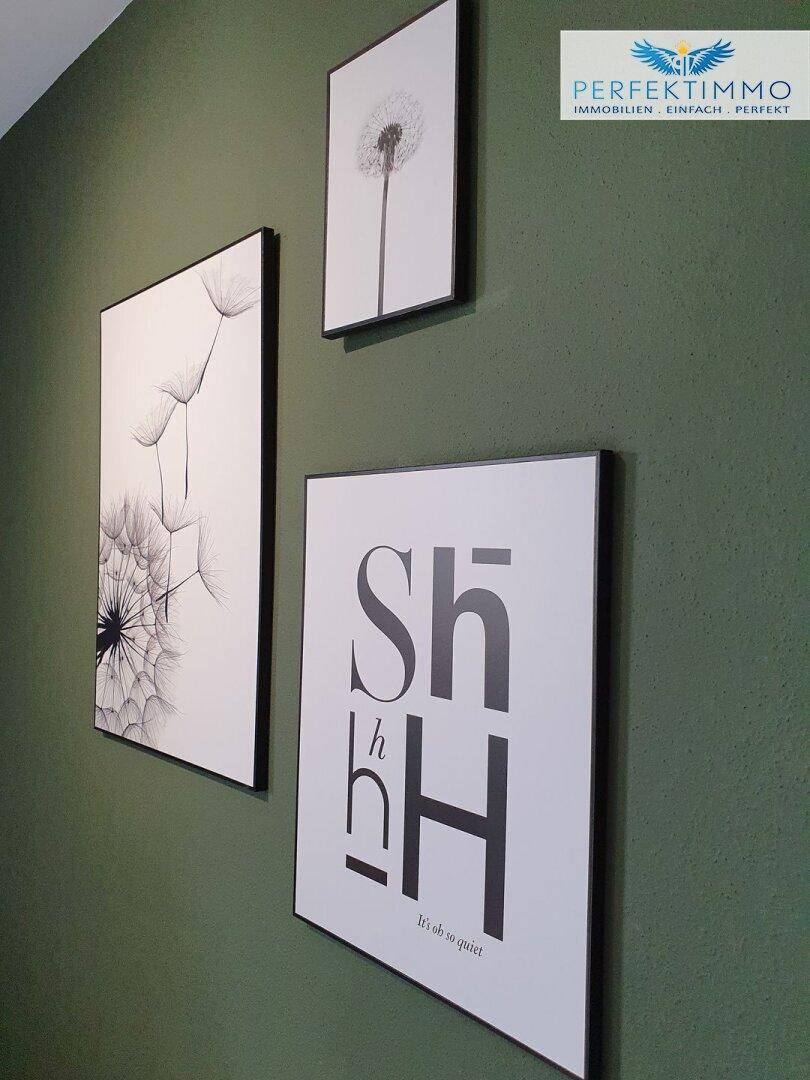 Grüne Wand mit modernen Schwarz-Weiß-Bildern und minimalistischer Dekoration.