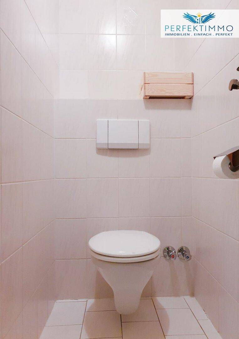 Separates WC mit Wand-WC und hellen Fliesen.