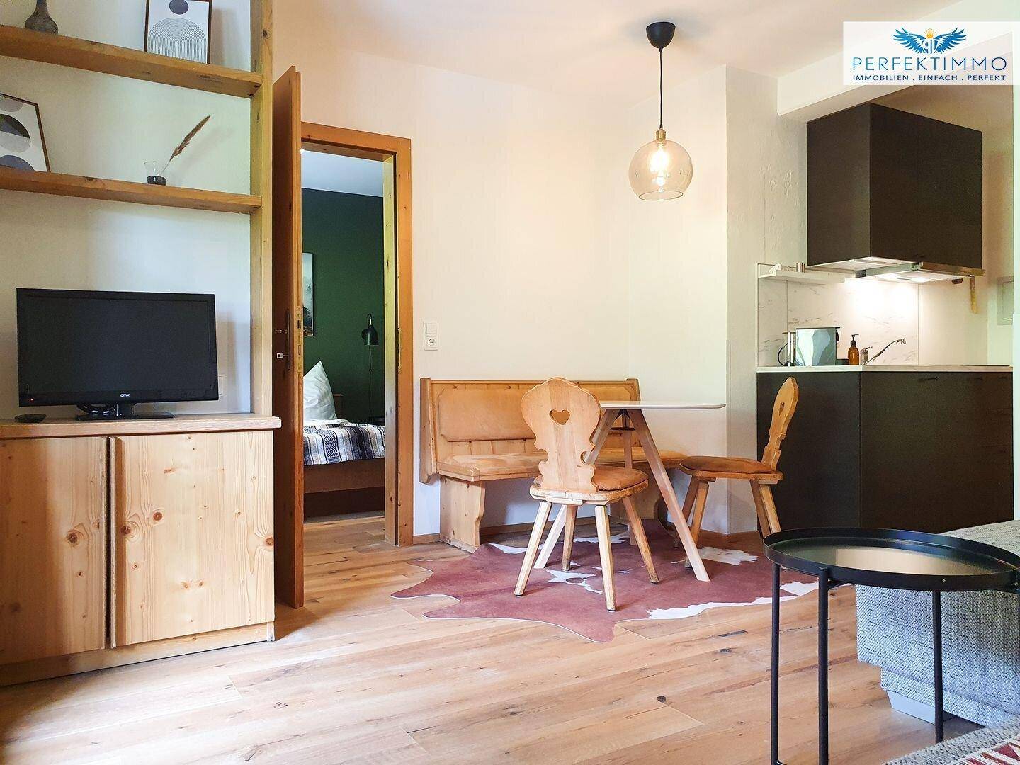 Offener Wohn- und Essbereich mit Holzboden und Zugang zum Schlafzimmer.