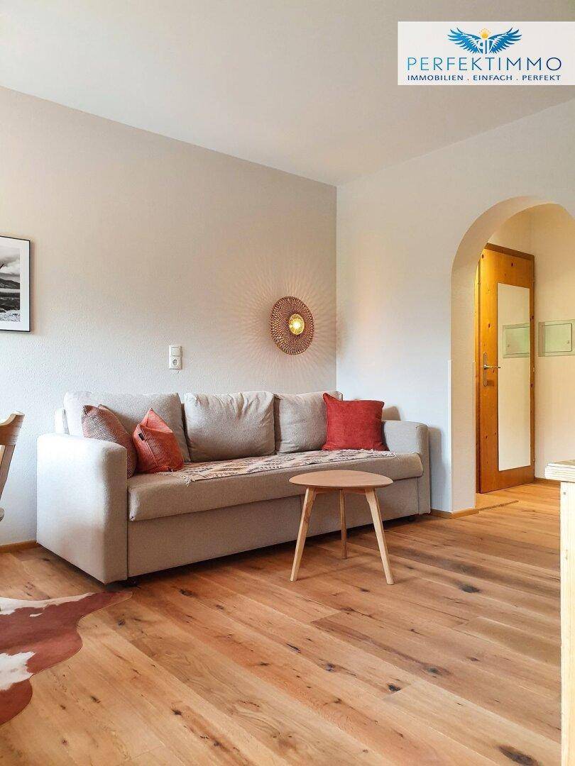 Gemütlicher Wohnbereich mit hellem Sofa, Holzboden und runden Beistelltisch.