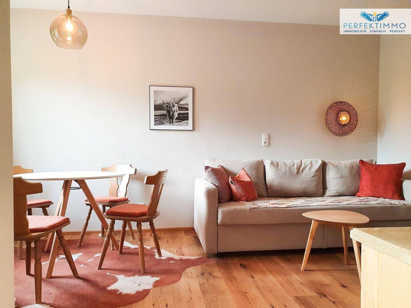 Offener Wohn- und Essbereich mit hellem Sofa, Holztisch und Stühlen.