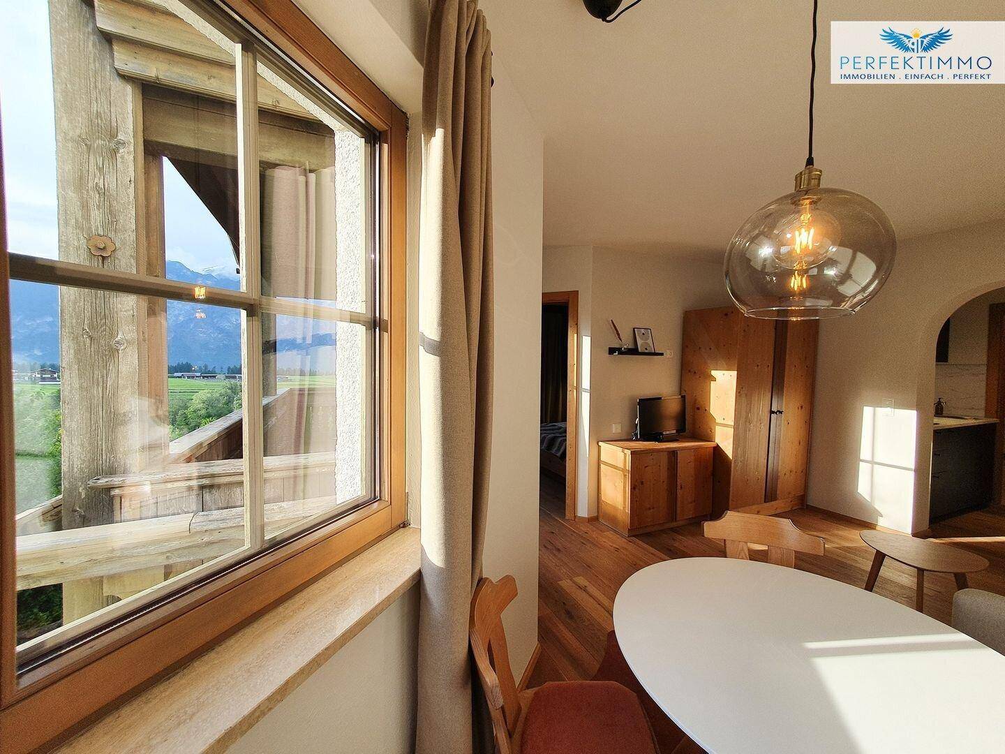 Heller Wohn- und Essbereich mit Bergblick durch große Fenster und Holzelementen.