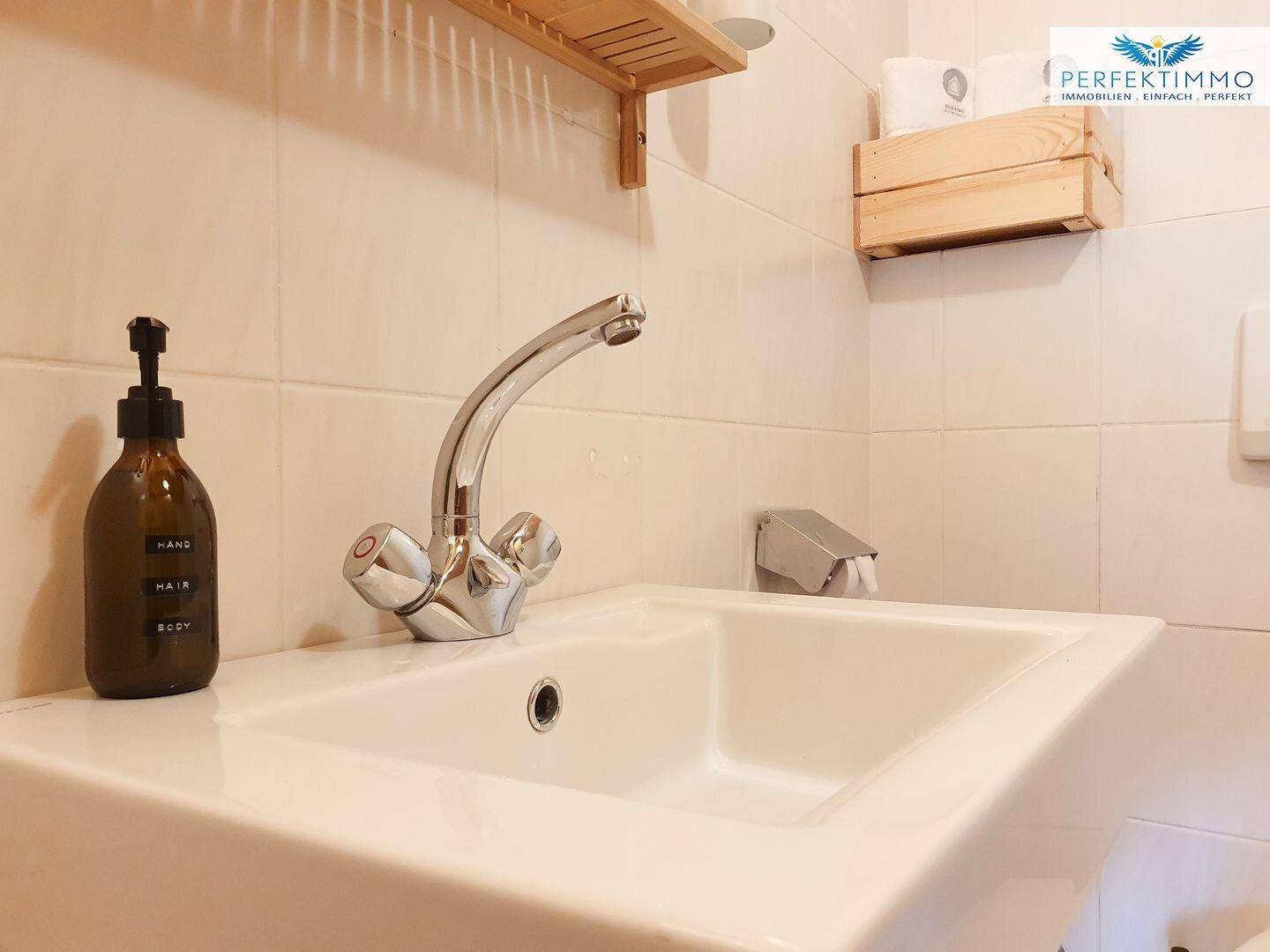 Nahaufnahme eines modernen Waschbeckens mit Wasserhahn und Seifenspender in einem WC.