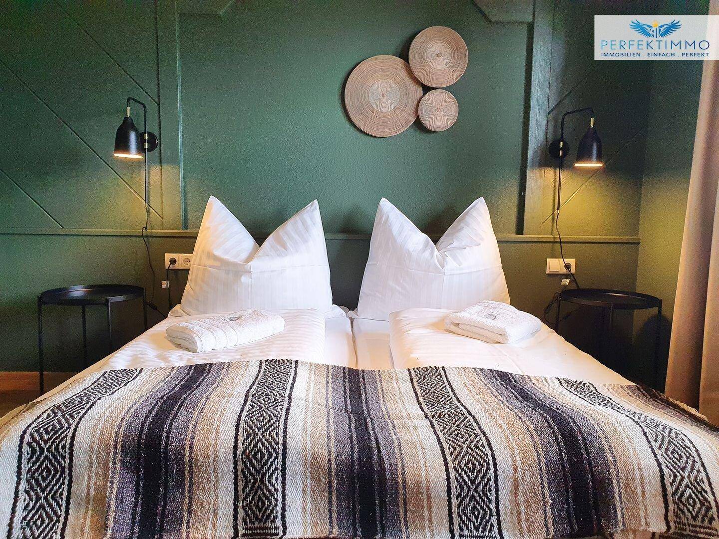 Gemütliches Doppelbett mit gestreifter Decke und grüner Wand im Schlafzimmer.