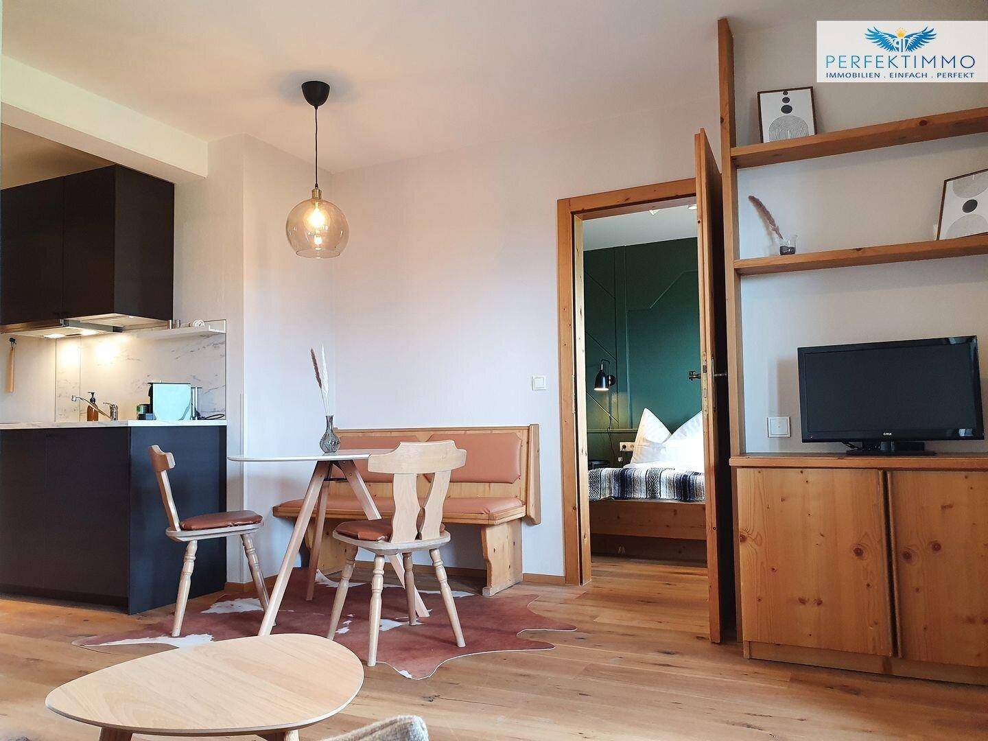 Offener Wohnbereich mit Küchenzeile, Essplatz und Blick in das angrenzende Schlafzimmer.