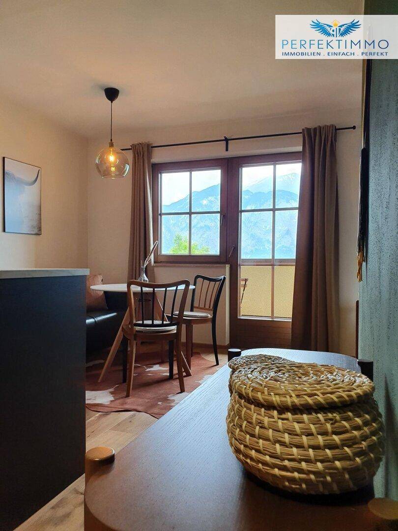Essbereich mit Holztisch und Stühlen, bietet einen schönen Bergblick durch die Fenster.