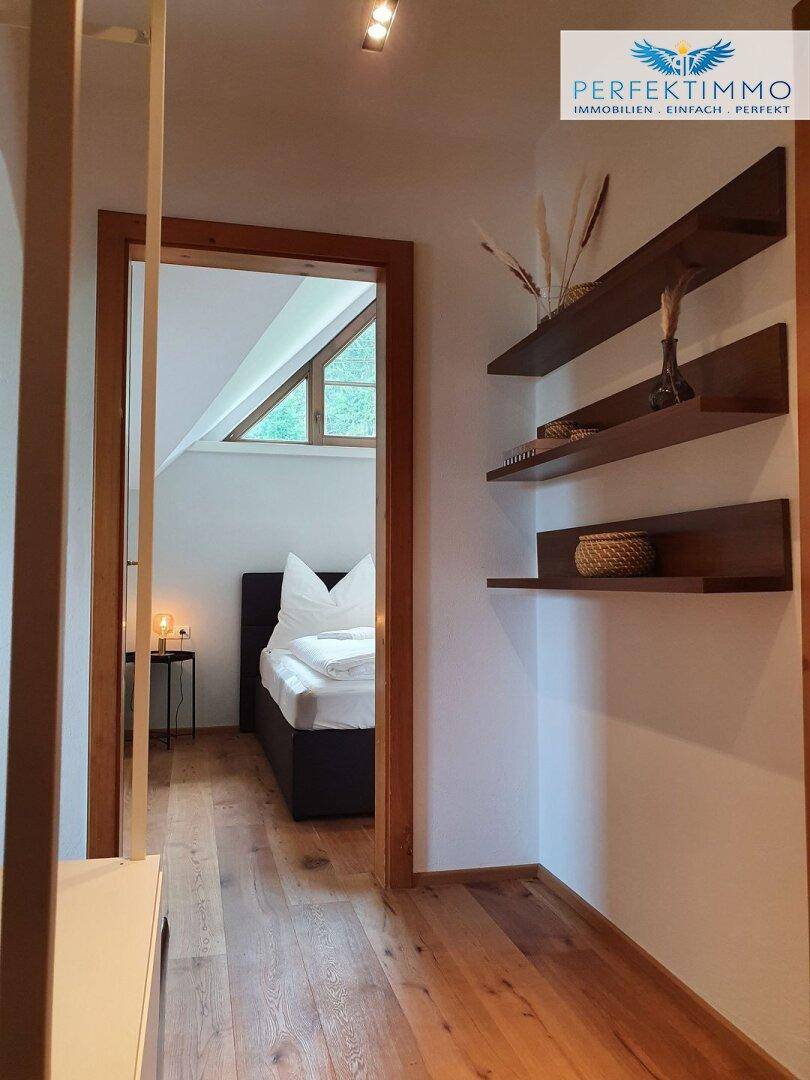 Heller Flur mit Holzregalen und Zugang zu einem gemütlichen Schlafzimmer.