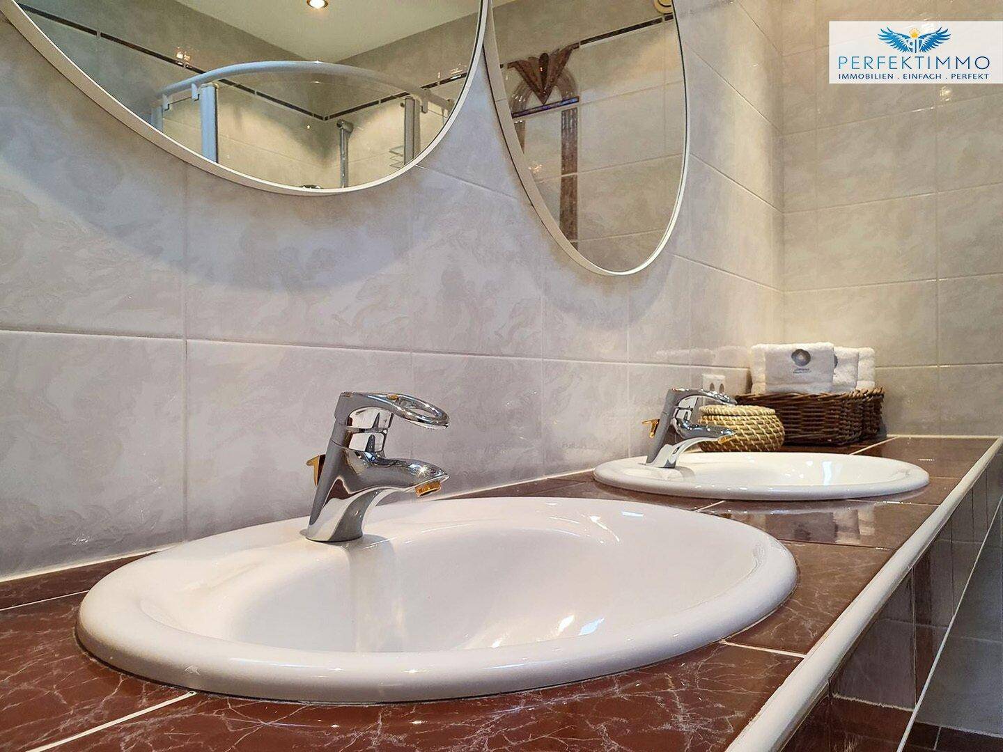 Doppelwaschbecken mit modernen Armaturen in einem gefliesten Badezimmer.