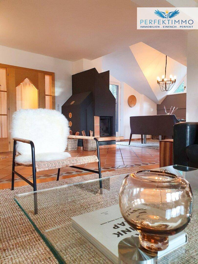 Wohnzimmer mit modernem Kamin, gemütlichem Sessel und Glastisch auf einem Teppich.