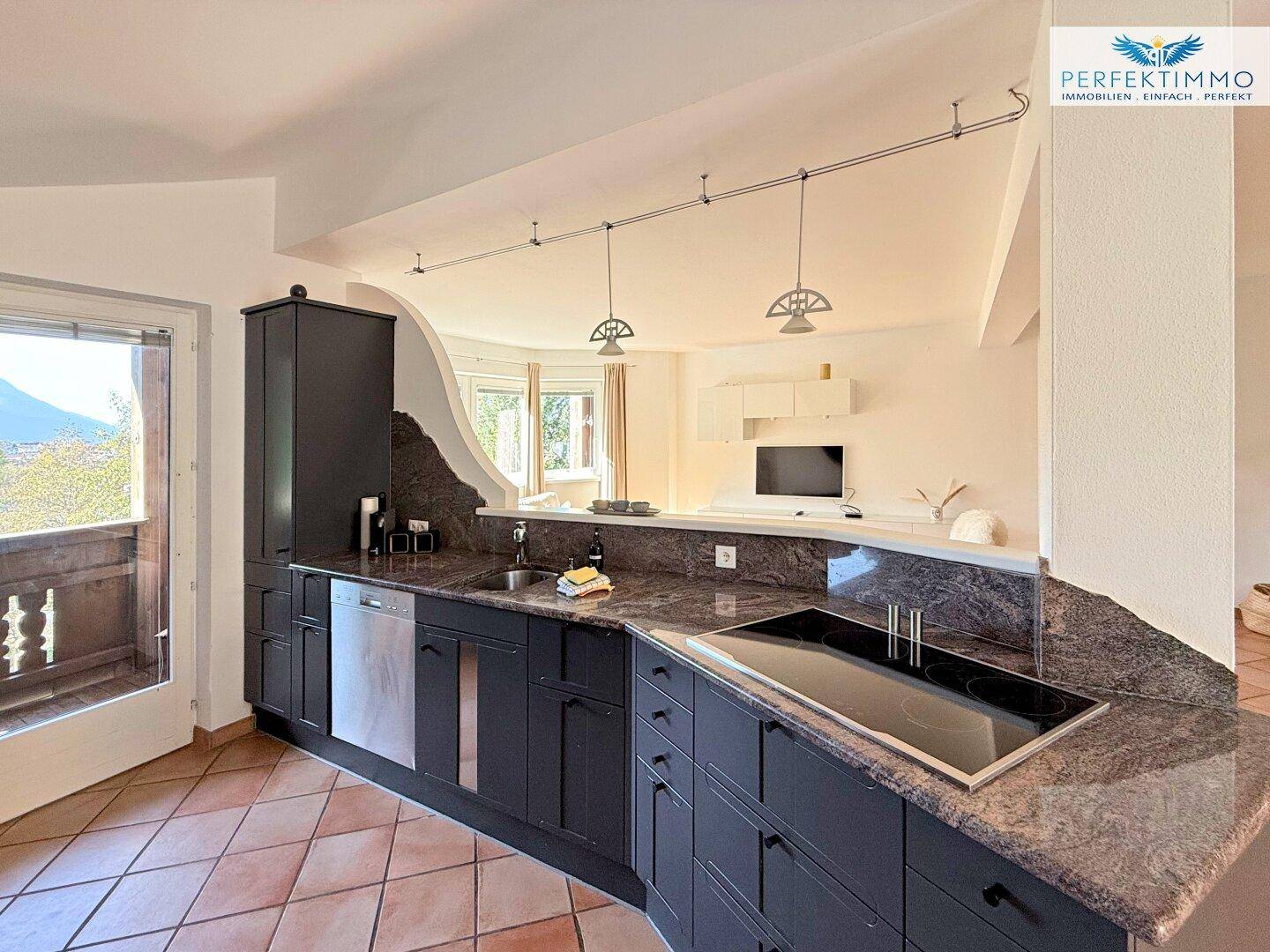 Moderne Küche mit Granitarbeitsplatten, Einbaugeräten und Zugang zu einem Balkon.