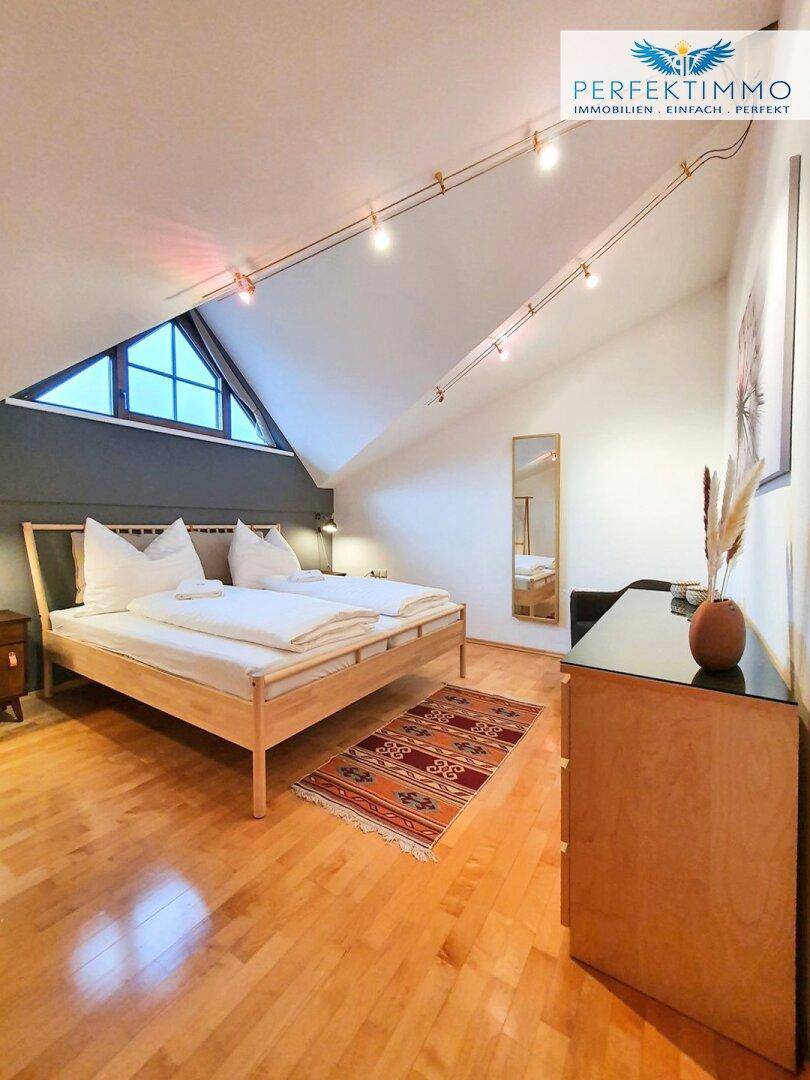 Helles Schlafzimmer im Dachgeschoss mit Holzboden, Dachschräge und einem gemütlichen Doppelbett.