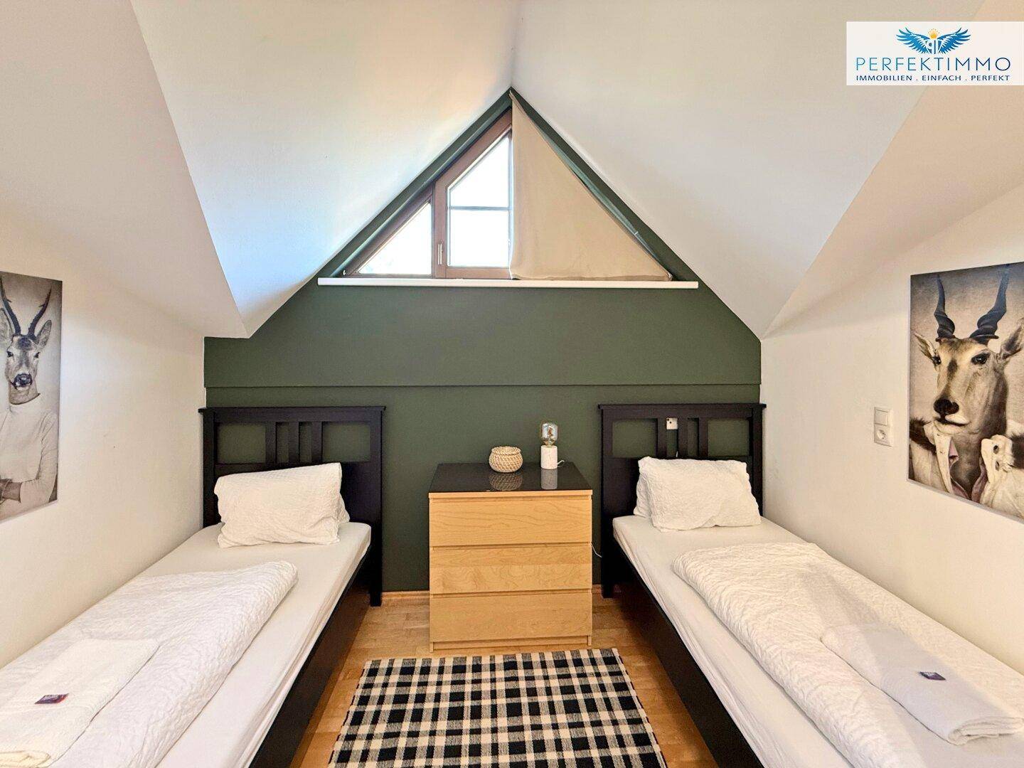 Helles Schlafzimmer mit zwei Einzelbetten, Holzboden und einer grünen Akzentwand.