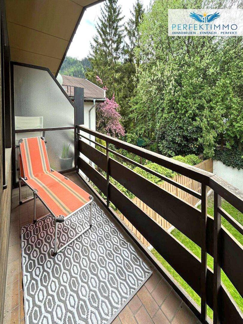 Balkon mit Liegestuhl und Geländer, bietet einen schönen Blick ins Grüne.