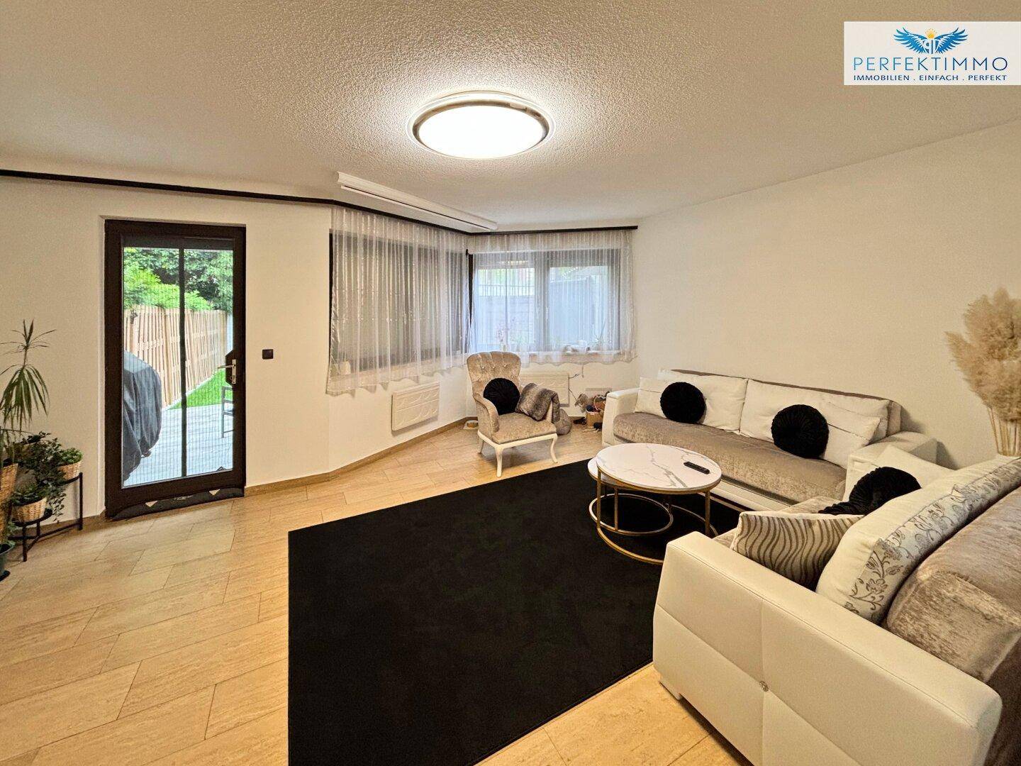 Gemütliches Wohnzimmer mit bequemen Sofas, Couchtisch und großen Fenstern für viel Tageslicht.