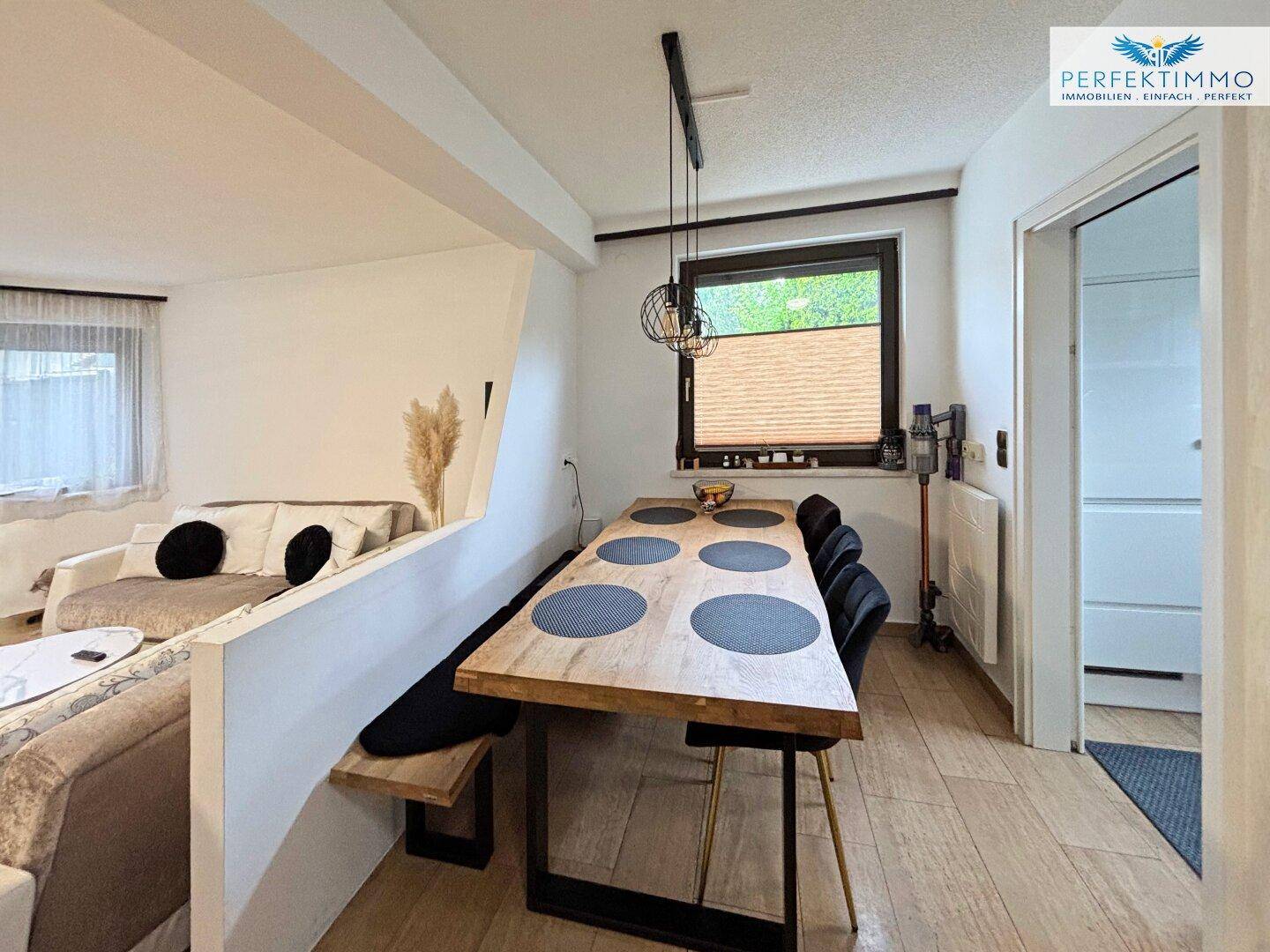 Essbereich mit rustikalem Holztisch und Sitzbank, offen zum Wohnzimmer hin gestaltet.
