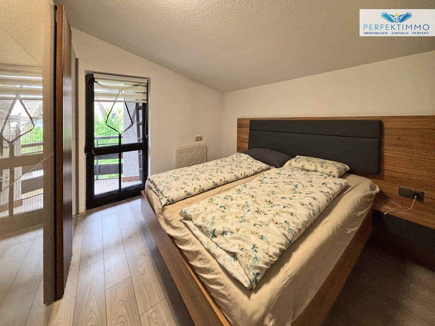 Schlafzimmer mit Doppelbett, Holzfußboden und direktem Zugang zu einem Balkon.