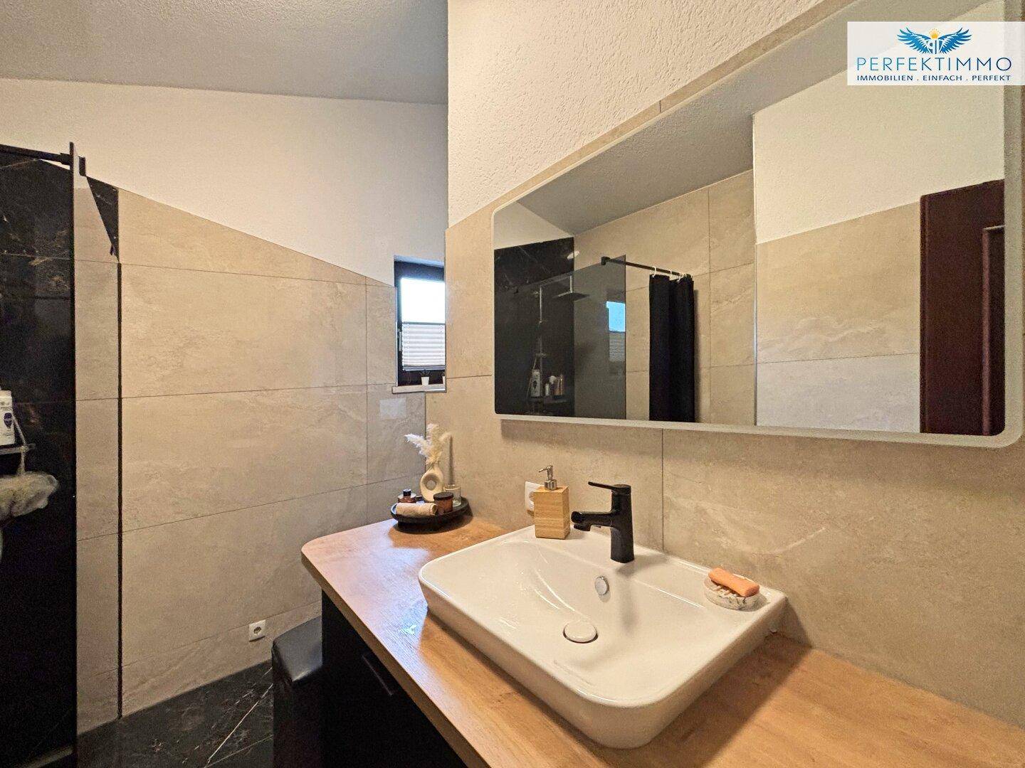 Modernes Badezimmer mit Einzelwaschbecken, Holzplatte und großem Spiegel.