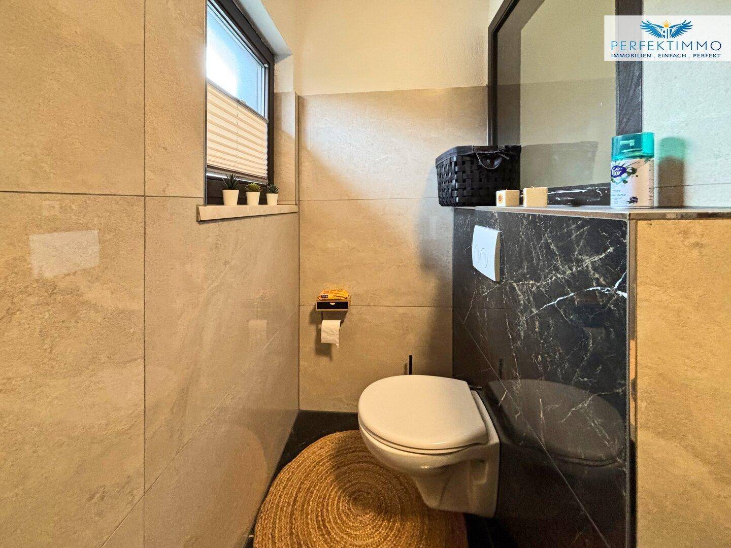 Toilettenbereich im Badezimmer mit wandhängendem WC und kleinem Fenster für Belüftung.