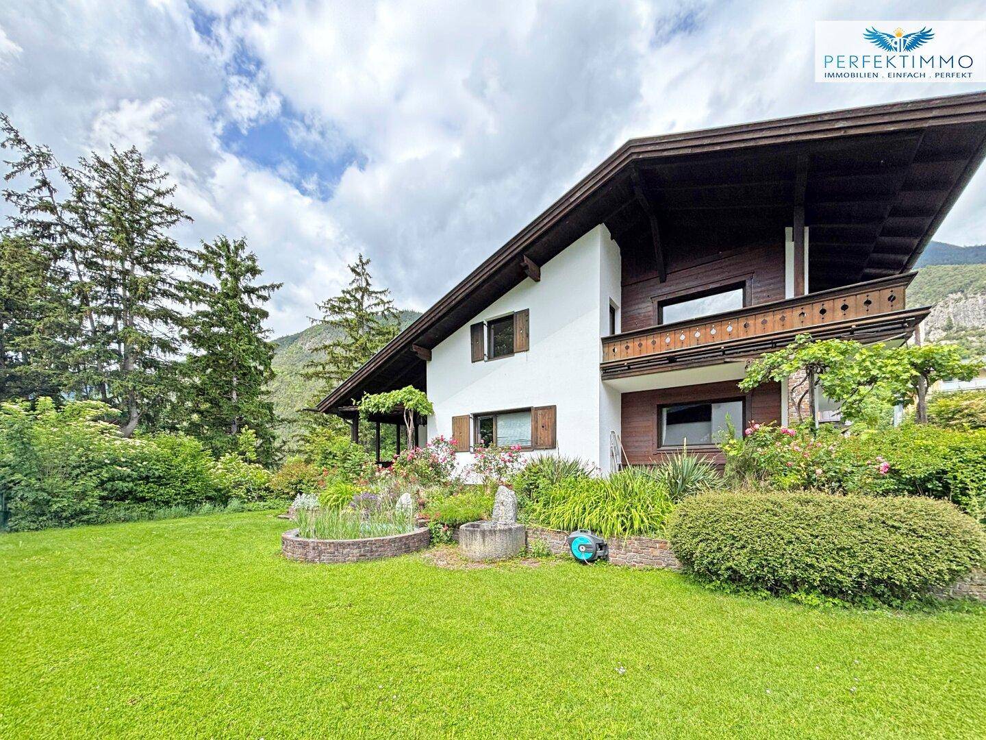 Charmantes Einfamilienhaus mit gepflegtem Garten und Blick auf die umliegende Berglandschaft.