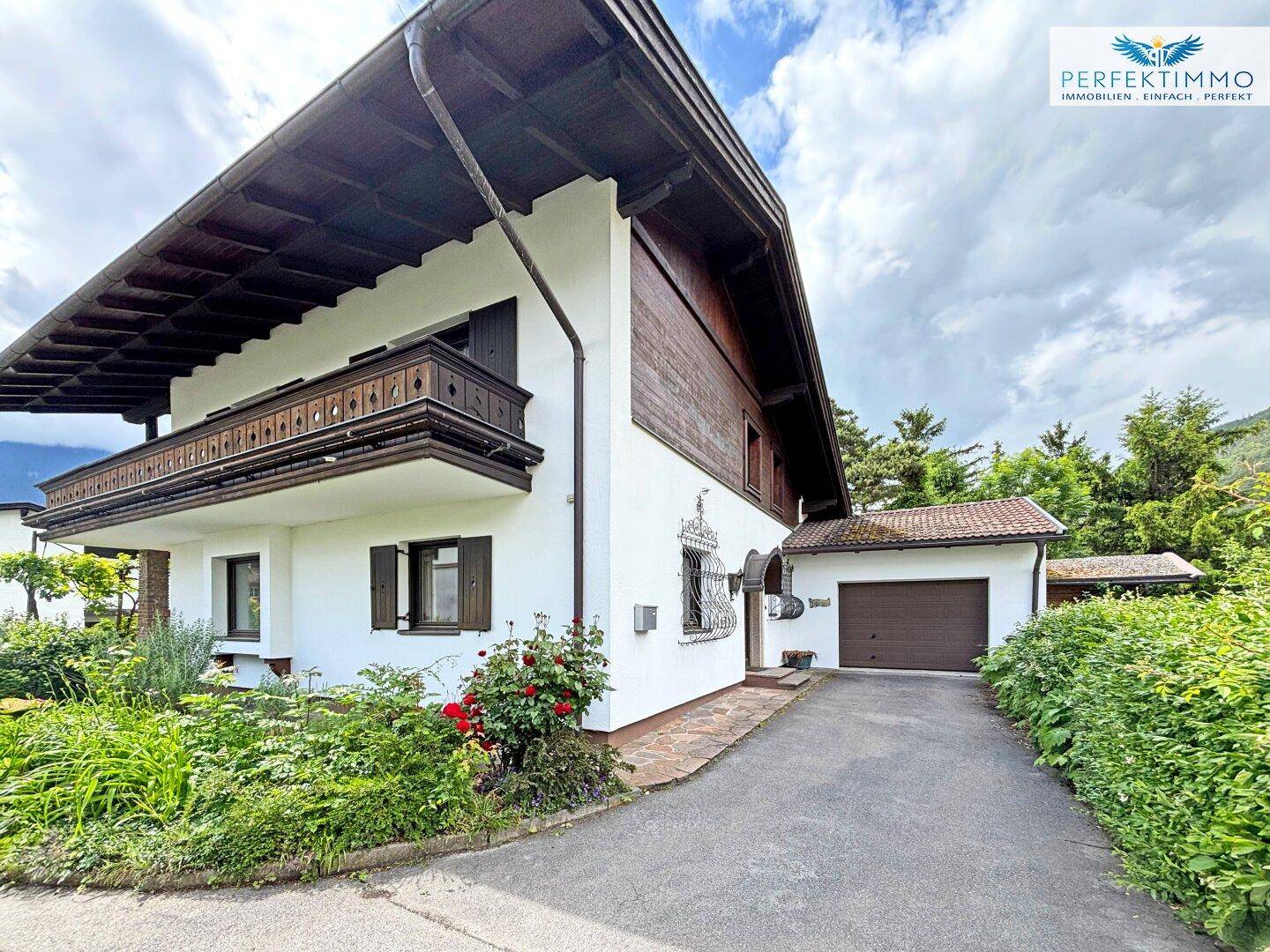 Seitenansicht des Hauses mit Einfahrt, Garage und gepflegter Bepflanzung.