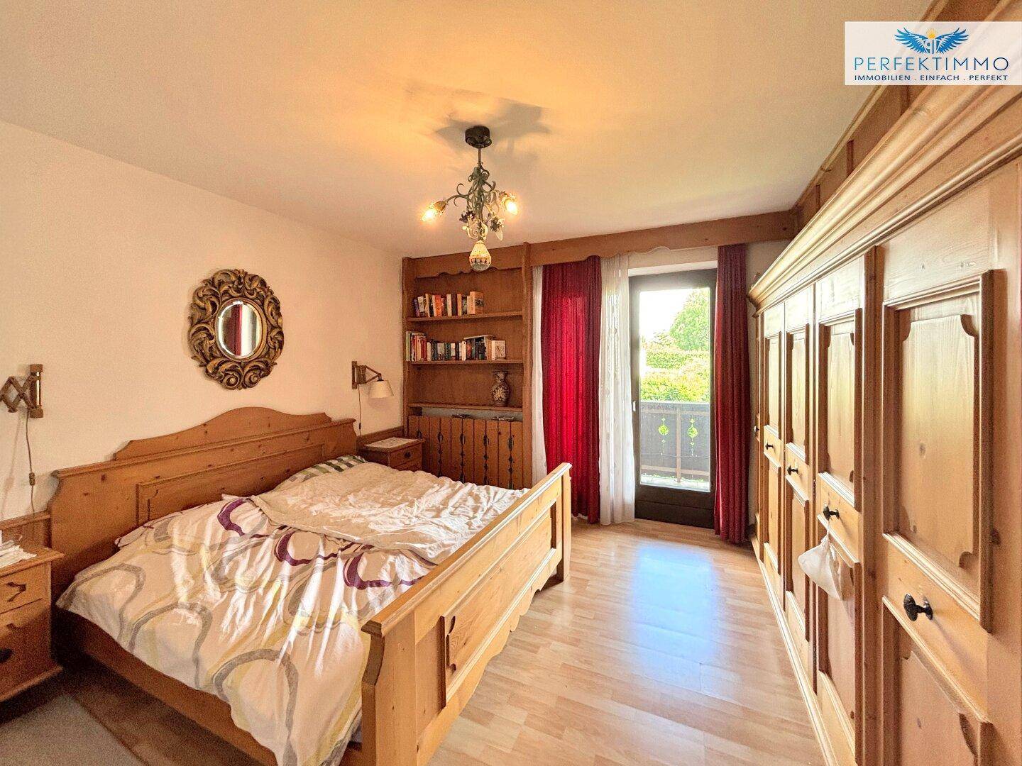 Gemütliches Schlafzimmer mit Holzmöbeln, großem Kleiderschrank und Zugang zum Balkon.