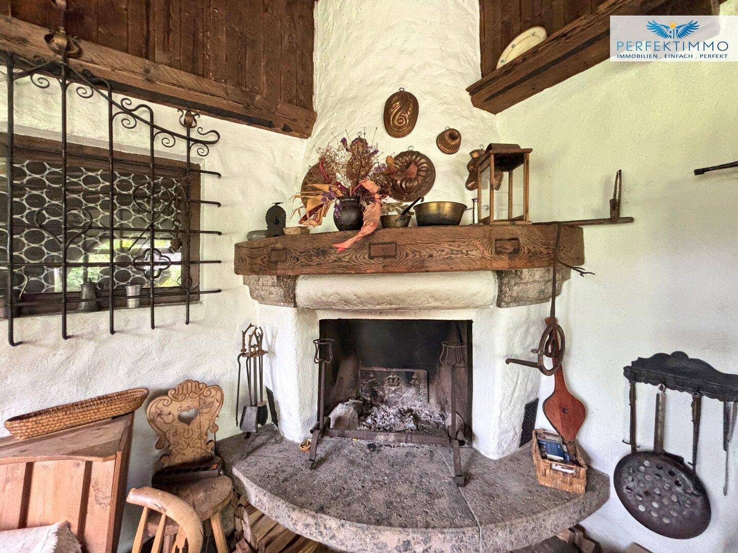 Gemütlicher traditioneller Kamin mit Steinsockel und Holzbalken, umgeben von rustikalen Dekorationen.