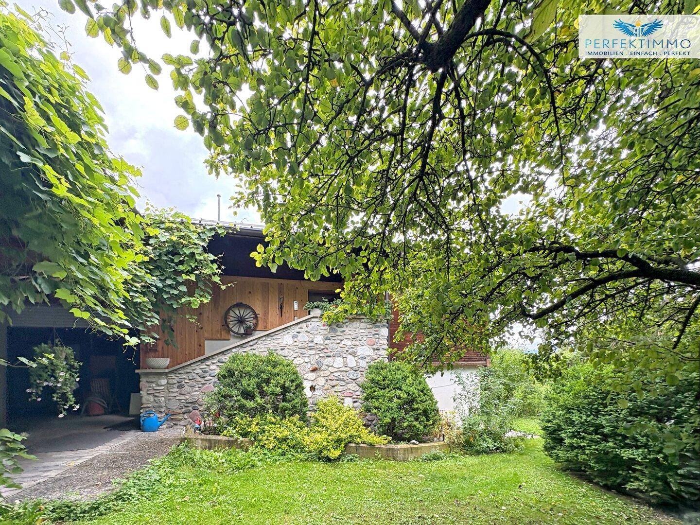 Charmantes Holzhaus mit Steinfundament, umgeben von einem gepflegten Garten und Bäumen.