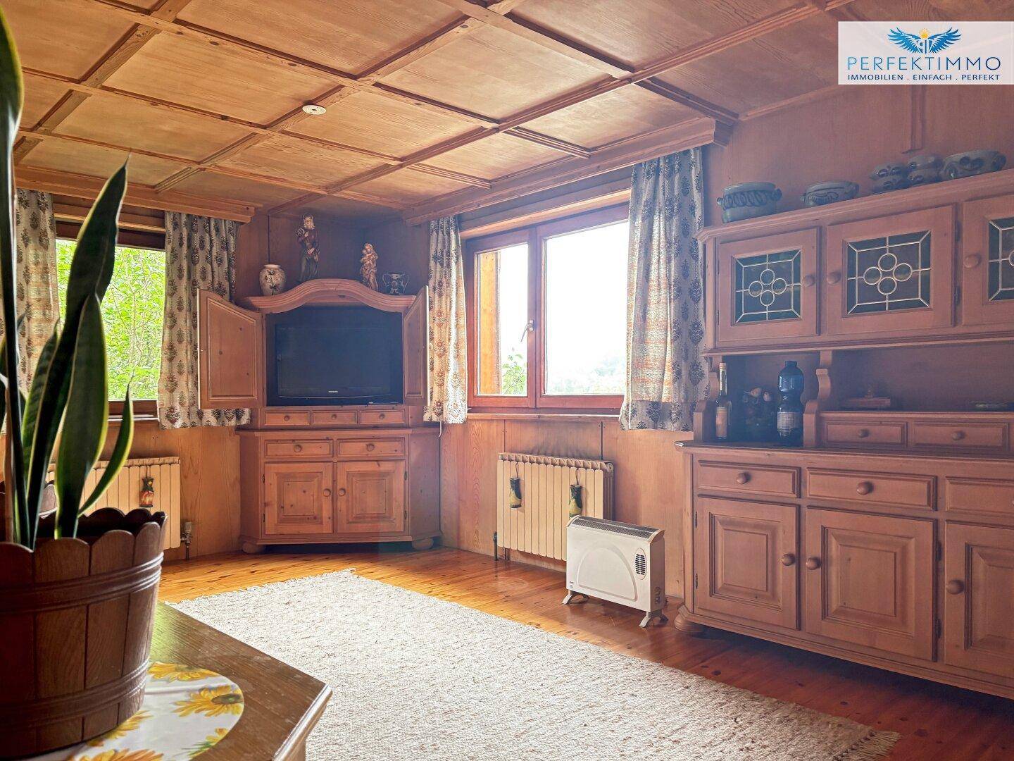 Gemütliches Wohnzimmer mit Holzwänden, Deckenvertäfelung und rustikalen Möbeln.