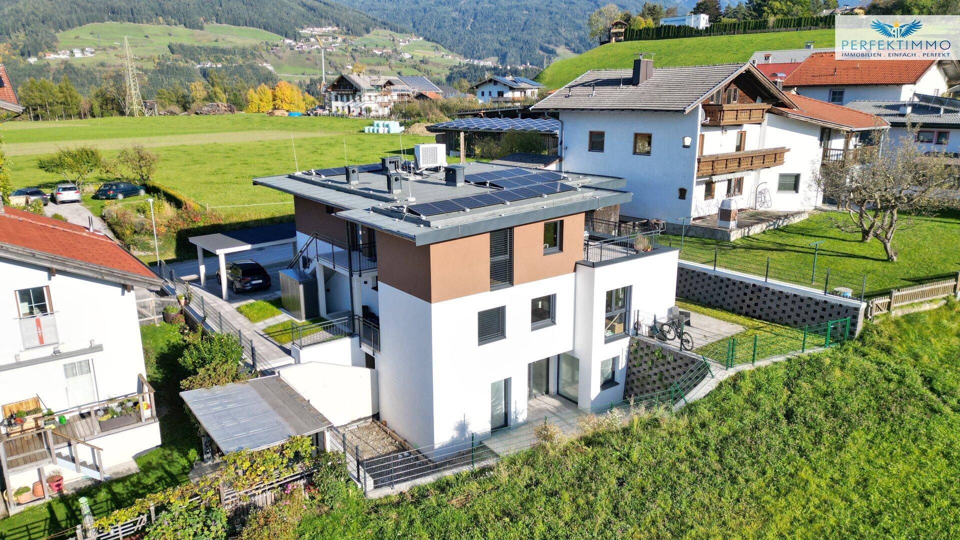 Vogelperspektive eines modernen Wohnhauses mit Solarpaneelen und weitläufiger Grünfläche.