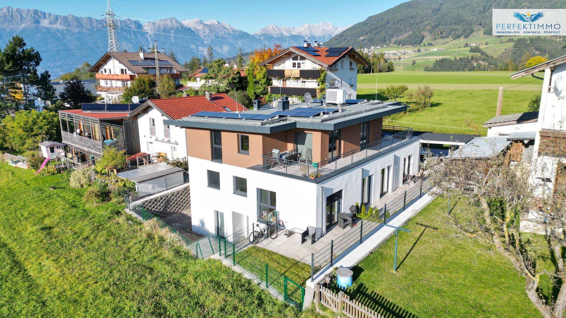 Luftaufnahme eines modernen Wohnhauses mit Solaranlage und großem Garten in ländlicher Umgebung.