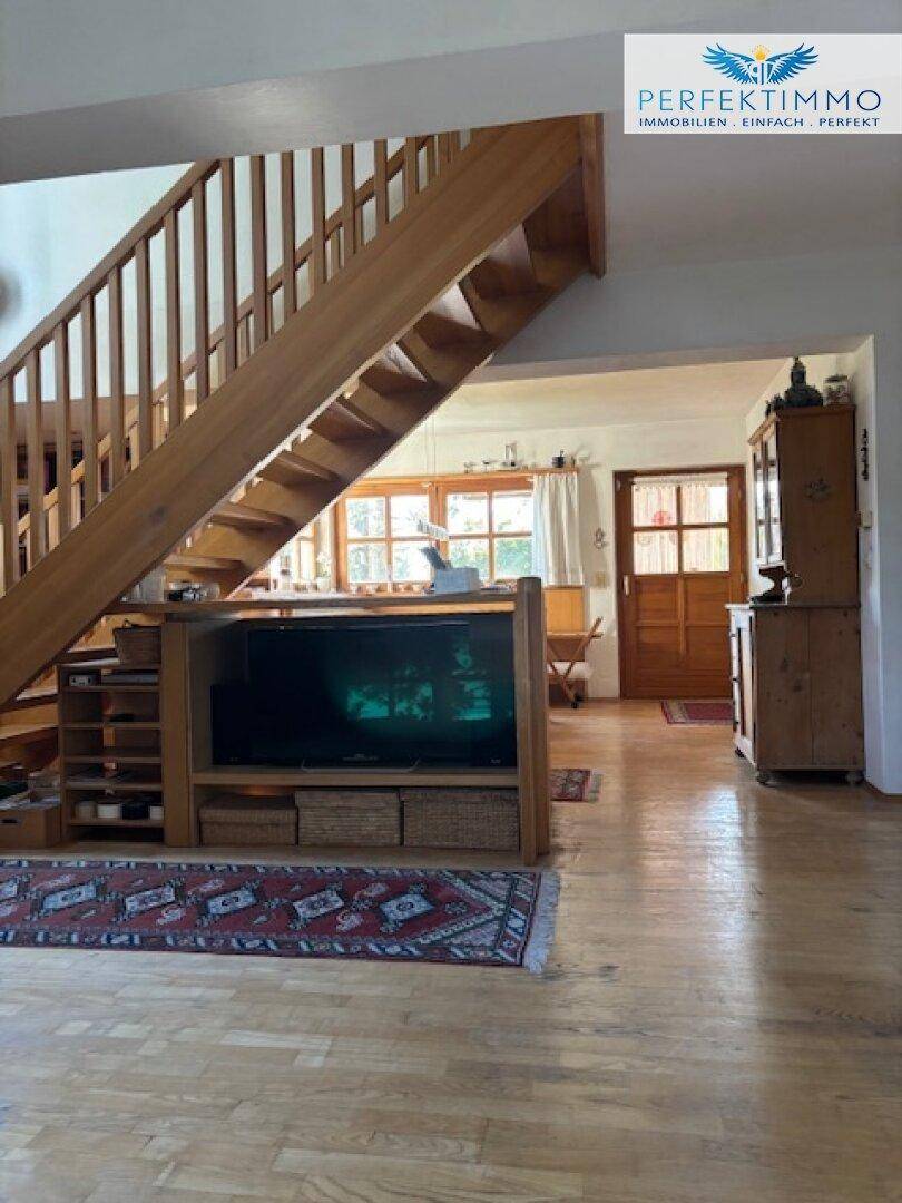 Offener Wohnbereich mit Holztreppe, TV-Möbel und Blick auf den Essbereich.