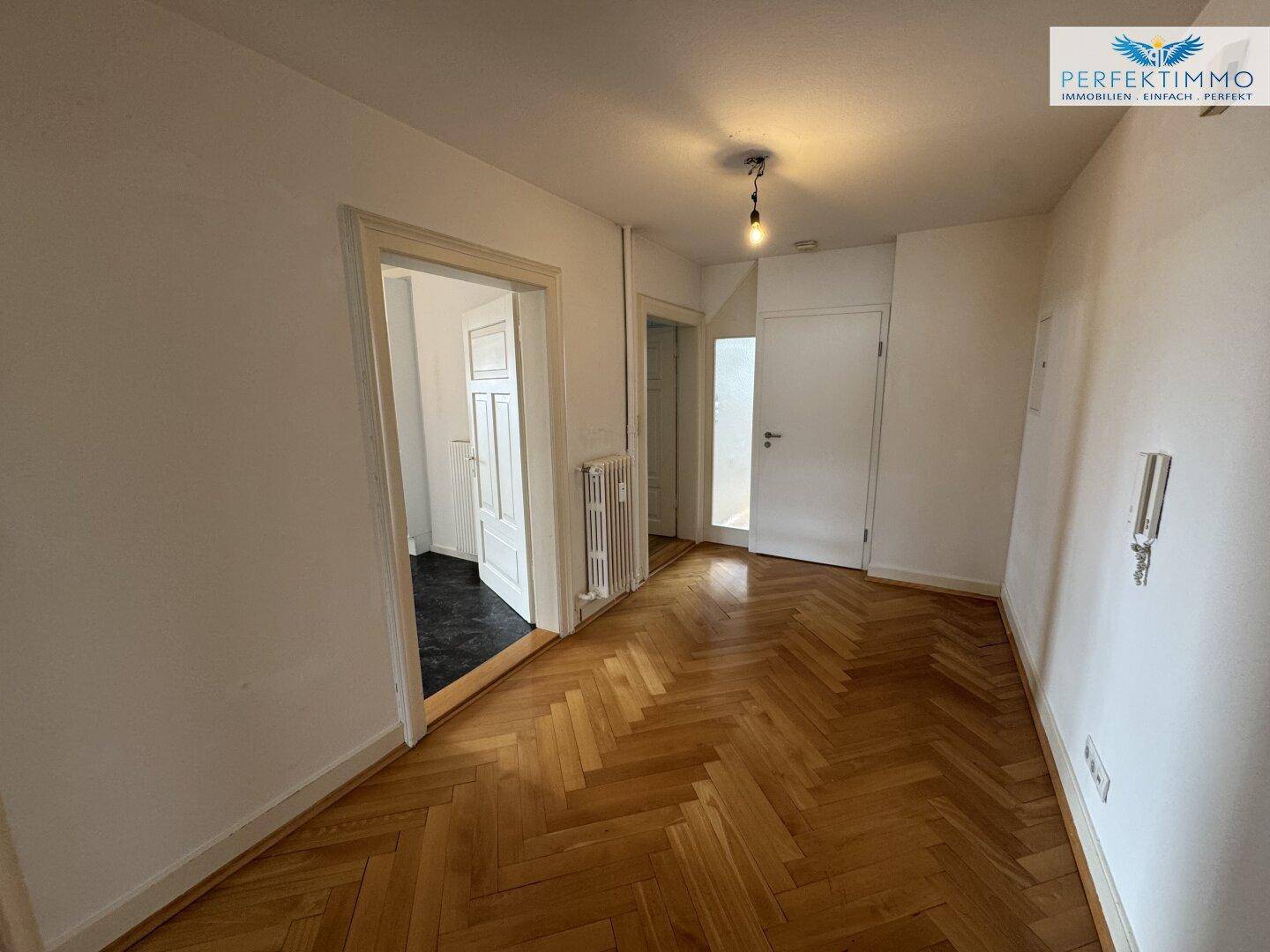 Flur mit Fischgrätparkettboden und Zugang zu weiteren Räumen der Wohnung.
