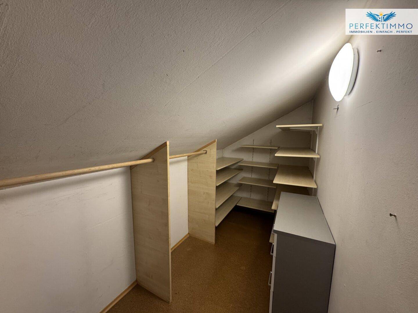 Praktischer Abstellraum unter der Dachschräge mit Regalen und Kleiderstange.