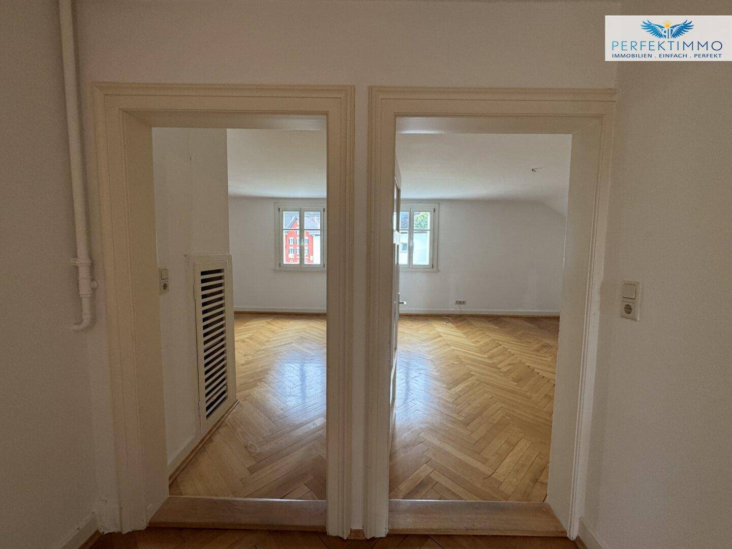 Blick durch zwei Türen in helle Räume mit klassischem Fischgrätparkettboden.