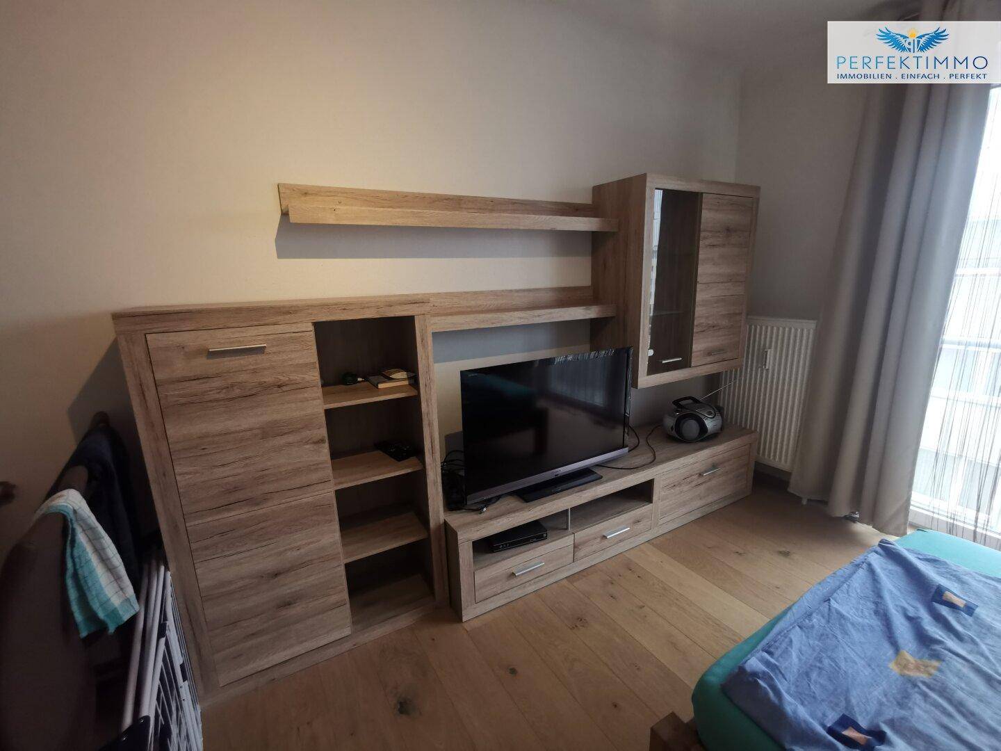 Gemütliches Schlafzimmer mit Holzboden und moderner Holzmöbelwand für Unterhaltung.