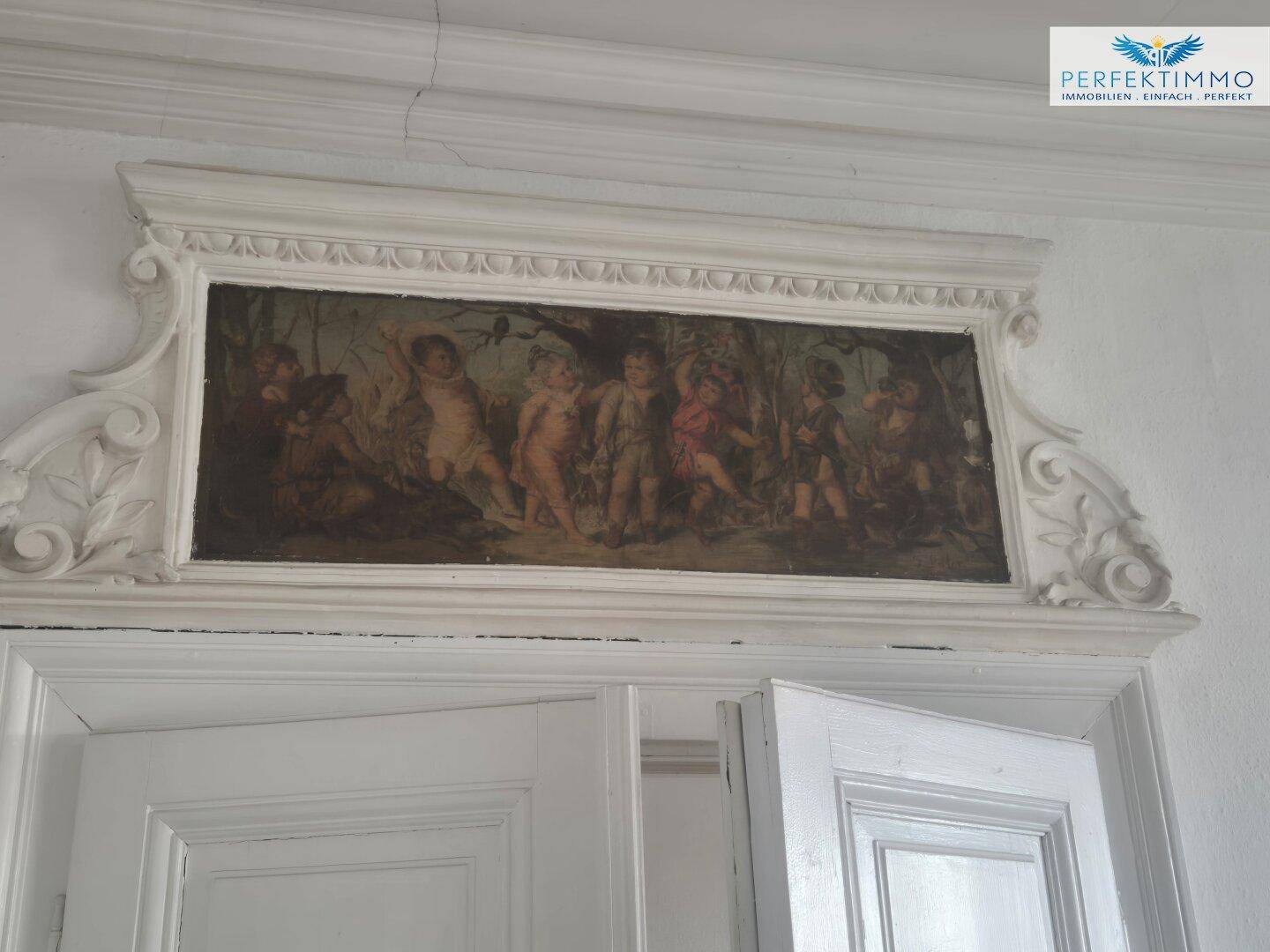 Historisches Gemälde über einem Türrahmen, umgeben von Stuckverzierungen, das den klassischen Stil hervorhebt.